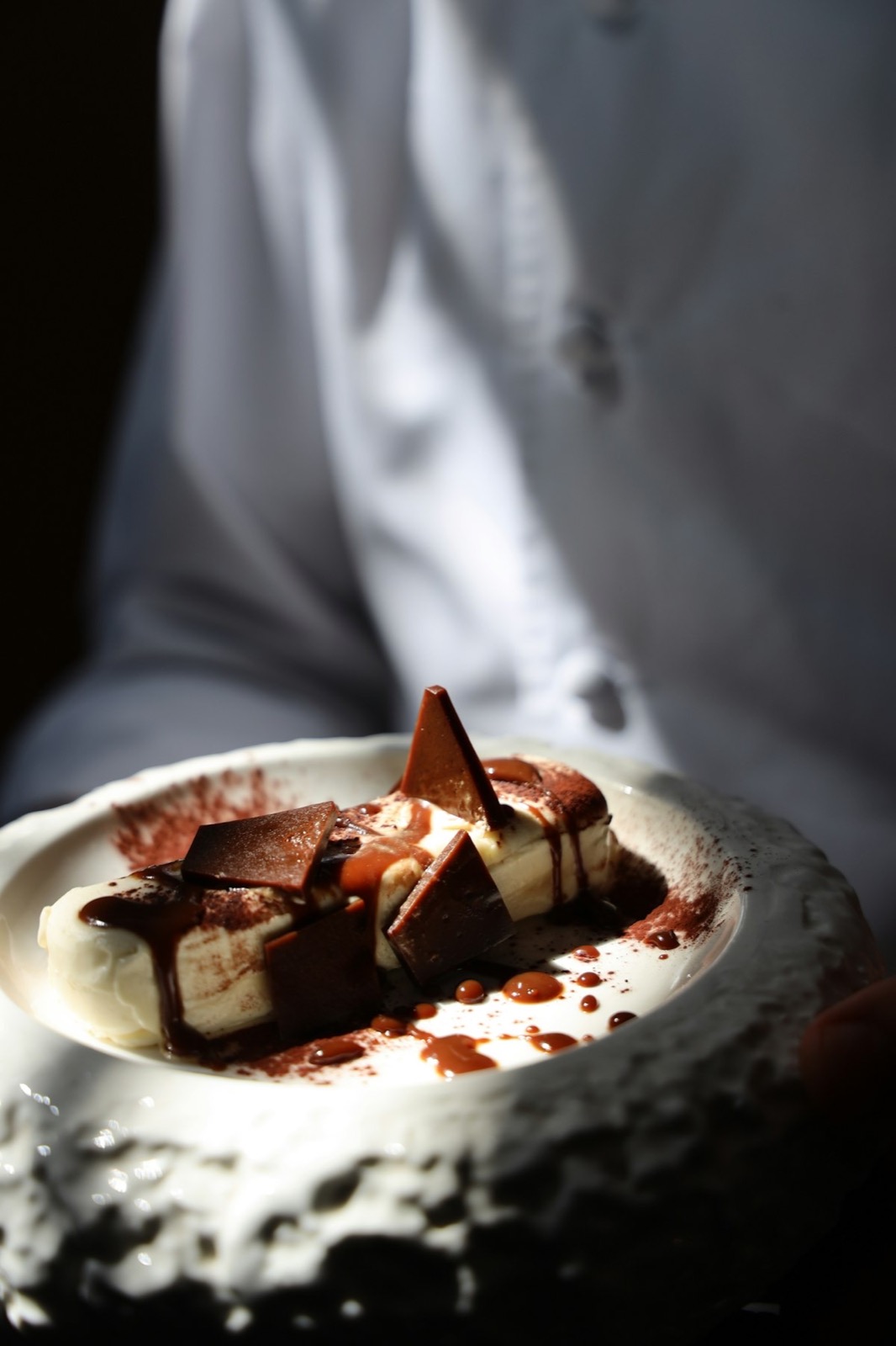 Desert od tamne čokolade sa kremom u keramičkoj činiji